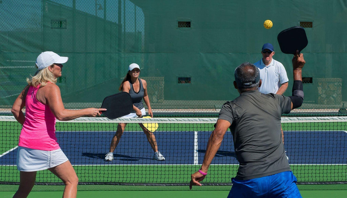 Four individuals engaged in a tennis match on a court showcasing dynamic movement and interaction with the ball